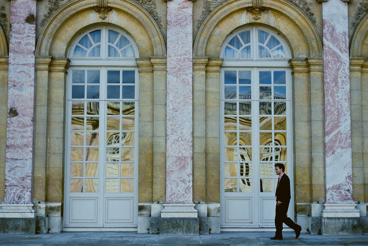 A Parisian flaneur walking past a striking building.